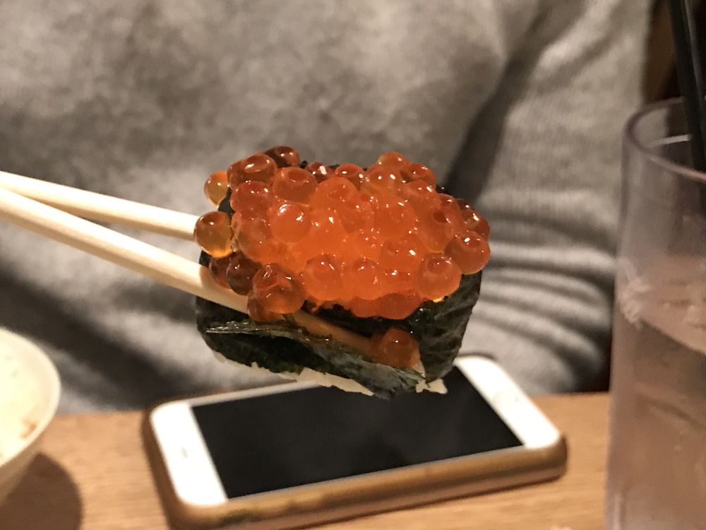 Salmon roe sushi held with chopsticks